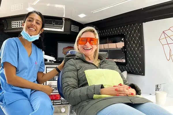 A patient and a clinician smiling inside the Mia mobile clinic
